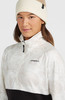 Model in einer cremefarbenen und beigen Mütze und einer weißen Jacke mit Aufdruck.