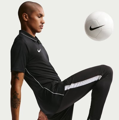 Ein Mann im schwarzen Nike-Shirt jongliert mit einem weißen Ball. Ein Mann im schwarzen Nike-Shirt jongliert mit einem weißen Ball.