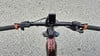 E-Bike-Lenker mit Display und orangefarbenen Griffen auf Asphalt.