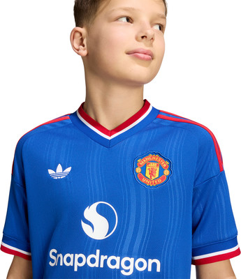 Junge im blauen Manchester United Fußballtrikot mit Snapdragon-Logo. Junge im blauen Manchester United Fußballtrikot mit Snapdragon-Logo.