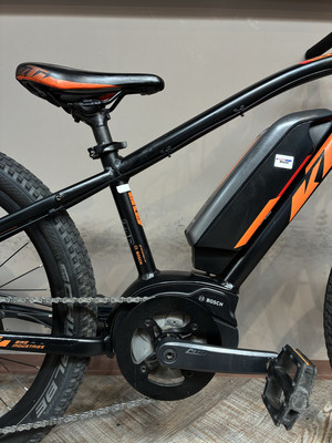 Schwarzes E-Bike mit orangefarbenen Details, Sattel und Akku.