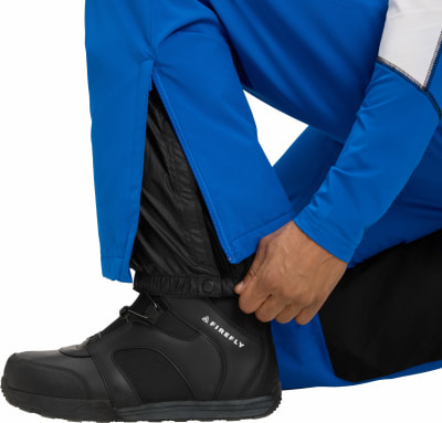 Ein Mann schließt den Reißverschluss einer blauen Skihose über einem schwarzen Futter. Ein Mann schließt den Reißverschluss einer blauen Skihose über einem schwarzen Futter.
