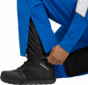 Ein Mann schließt den Reißverschluss einer blauen Skihose über einem schwarzen Futter.