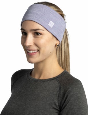Eine Frau mit einem lila Stirnband und einem dunklen Shirt vor weißem Hintergrund.