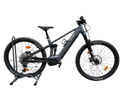 Graues E-Mountainbike mit Federung, auf einem Ständer stehend.