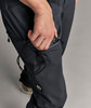 Eine Hand steckt einen kleinen Gegenstand in die Tasche einer dunklen Hose.