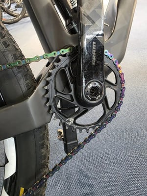 Bunter Fahrradkettenring am Mountainbike mit schwarzem Kettenblatt und SRAM-Kurbel.