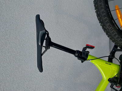 Grünes Fahrrad mit schwarzem Sattel und Rücklicht an der Wand.
