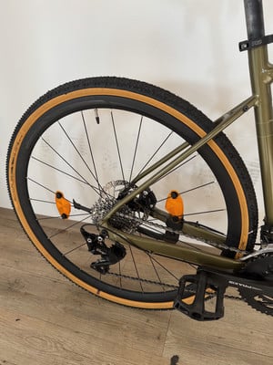 Grünes Fahrrad mit braunen Reifen und orangefarbenen Reflektoren am Hinterrad. Grünes Fahrrad mit braunen Reifen und orangefarbenen Reflektoren am Hinterrad.