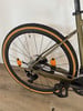 Grünes Fahrrad mit braunen Reifen und orangefarbenen Reflektoren am Hinterrad.