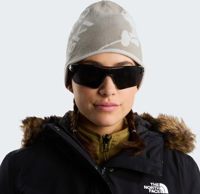 Eine Frau in einer Winterjacke, Mütze und Sonnenbrille mit The North Face Logo. Eine Frau in einer Winterjacke, Mütze und Sonnenbrille mit The North Face Logo.