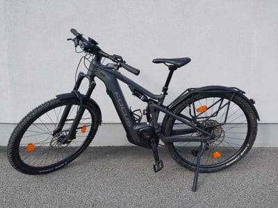 Ein schwarzes Focus E-Bike mit Federung und Gepäckträger steht vor einer Wand. Ein schwarzes Focus E-Bike mit Federung und Gepäckträger steht vor einer Wand.