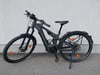 Ein schwarzes Focus E-Bike mit Federung und Gepäckträger steht vor einer Wand.