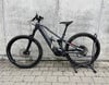 Ein graues Conway E-Bike steht vor einer Betonwand auf Pflastersteinen.