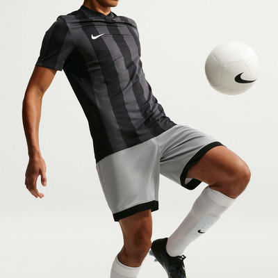 Fußballer im schwarzen Streifen-Trikot und grauen Shorts mit Ball.