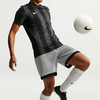 Fußballer im schwarzen Streifen-Trikot und grauen Shorts mit Ball.