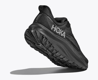 Černá běžecká bota HOKA s výraznou podrážkou a logem na boku. Černá běžecká bota HOKA s výraznou podrážkou a logem na boku.