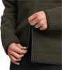 Detail von Händen, die einen dunkelgrünen Rippstrick-Pullover mit Reißverschluss schließen.