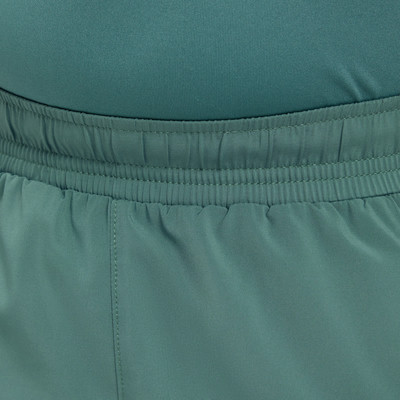 Detail elastického pasu tmavě zelených šortek s jemným prošíváním.