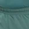 Detail elastického pasu tmavě zelených šortek s jemným prošíváním.