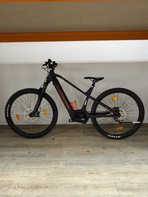 Ein schwarzes Lapierre E-Bike mit orangefarbenen Akzenten auf Holzboden. Ein schwarzes Lapierre E-Bike mit orangefarbenen Akzenten auf Holzboden.