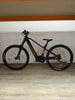 Ein schwarzes Lapierre E-Bike mit orangefarbenen Akzenten auf Holzboden.