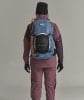 Rückansicht einer Person mit Rucksack und Skistöcken.
