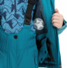Ein Kind trägt eine blaue Winterjacke und Skihosen mit einem Stern.