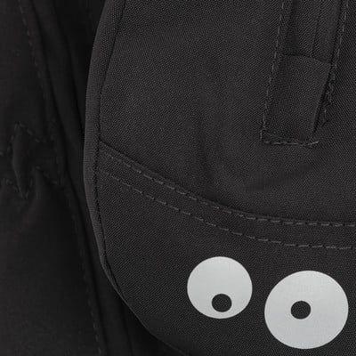 Detail eines schwarzen Rucksacks mit zwei reflektierenden Augen und Nähten. Detail eines schwarzen Rucksacks mit zwei reflektierenden Augen und Nähten.