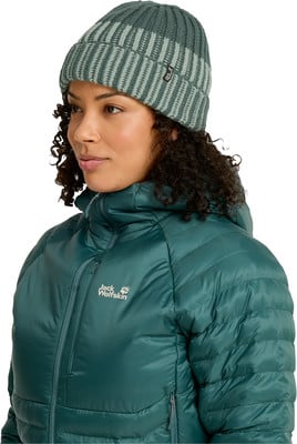 Eine Frau mit lockigem Haar trägt eine grüne Jacke und eine gestreifte Mütze. Eine Frau mit lockigem Haar trägt eine grüne Jacke und eine gestreifte Mütze.
