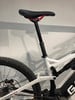 Ein Teil eines Mountainbikes mit weißem Rahmen und schwarzem Sattel.
