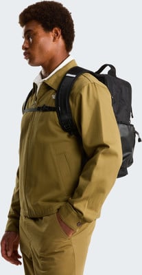 Ein junger Mann mit braunen Haaren trägt eine Khaki-Jacke und Rucksack. Ein junger Mann mit braunen Haaren trägt eine Khaki-Jacke und Rucksack.