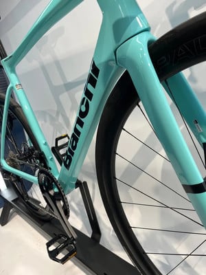 Detail eines hellblauen Bianchi Rennradrahmens mit Markenlogo.