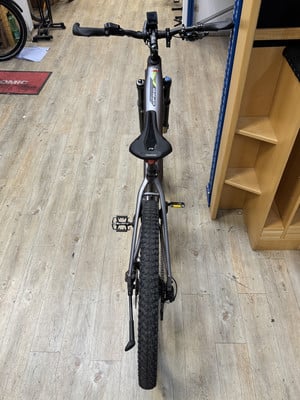 Silbernes E-Bike mit Stoßdämpfern und breiten Reifen auf Holzboden. Silbernes E-Bike mit Stoßdämpfern und breiten Reifen auf Holzboden.