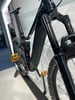 Schwarzes E-Bike mit gelben Pedalen auf einem Ständer.