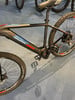 Detail eines Genesis Elektro-Mountainbikes mit blauem und rotem Streifen am Rahmen.