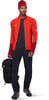 Ein Mann in einer roten Jacke und schwarzer Hose mit Rucksack und Schuhen.