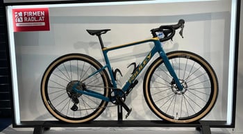Ein blaues Ridley Gravelbike mit beige Reifen und goldenen Akzenten.