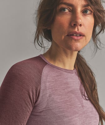 Eine Frau in einem rosafarbenen Langarmshirt blickt zur Seite. Eine Frau in einem rosafarbenen Langarmshirt blickt zur Seite.