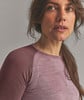 Eine Frau in einem rosafarbenen Langarmshirt blickt zur Seite.