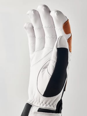 Detail eines weißen Handschuhs mit braunen und schwarzen Akzenten auf hellem Hintergrund. Detail eines weißen Handschuhs mit braunen und schwarzen Akzenten auf hellem Hintergrund.