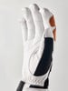 Detail eines weißen Handschuhs mit braunen und schwarzen Akzenten auf hellem Hintergrund.