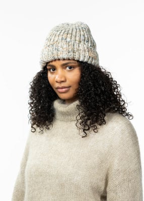 Eine Frau mit lockigem Haar trägt eine Strickmütze und einen Pullover. Eine Frau mit lockigem Haar trägt eine Strickmütze und einen Pullover.