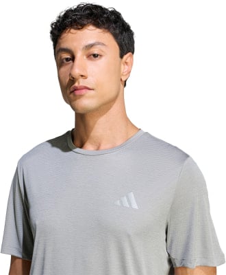 Mann in einem grauen T-Shirt mit Adidas-Logo auf der Brust. Mann in einem grauen T-Shirt mit Adidas-Logo auf der Brust.