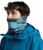 Ein Mann in einer blauen Jacke mit einem gemusterten Schal um den Hals.