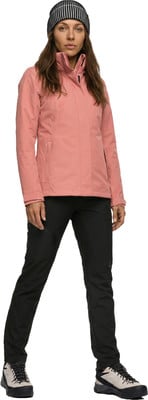 Eine Frau in einer rosa Jacke, schwarzen Hose und gestreiftem Hut steht. Eine Frau in einer rosa Jacke, schwarzen Hose und gestreiftem Hut steht.