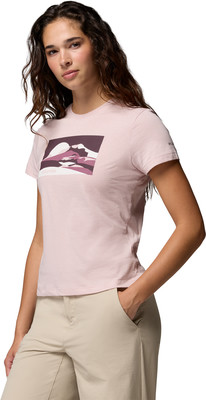 Frau in einem rosa T-Shirt mit Bergaufdruck und einer beigen Hose mit Tasche. Frau in einem rosa T-Shirt mit Bergaufdruck und einer beigen Hose mit Tasche.