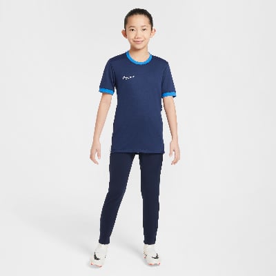Ein Junge im dunkelblauen Nike-Trikot und dunklen Hosen steht vor einem weißen Hintergrund. Ein Junge im dunkelblauen Nike-Trikot und dunklen Hosen steht vor einem weißen Hintergrund.