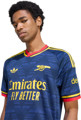 Ein Mann in einem dunkelblauen Arsenal-Fußballtrikot mit Adidas- und Emirates-Logo. Ein Mann in einem dunkelblauen Arsenal-Fußballtrikot mit Adidas- und Emirates-Logo.