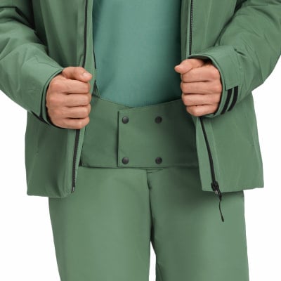Ein Mann schließt eine grüne Winterjacke über einem helleren Hemd und einer Hose. Ein Mann schließt eine grüne Winterjacke über einem helleren Hemd und einer Hose.